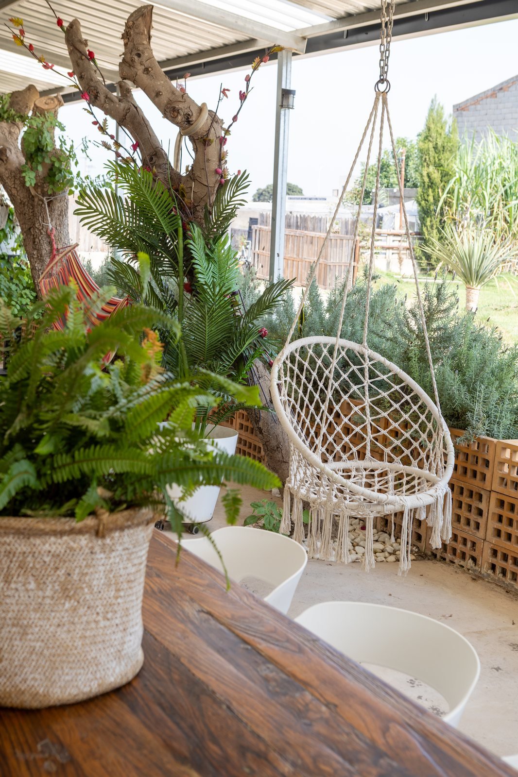 Porche con silla colgante de macramé y plantas junto al apartamento Bahía