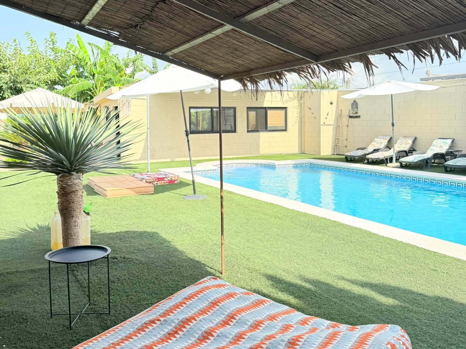 Camas balinesas bajo la pérgola de cañizo, junto a la piscina